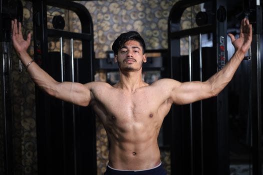 pexels-photo-11661410-11661410 A shirtless South Asian man shows off his muscular physique while posing in a gym setting.