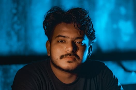 pexels-photo-20542649-20542649 Close-up portrait of a young man with a thoughtful expression against a blue backdrop.